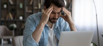 Upset businessman touching temples, suffering from strong headache at workplace